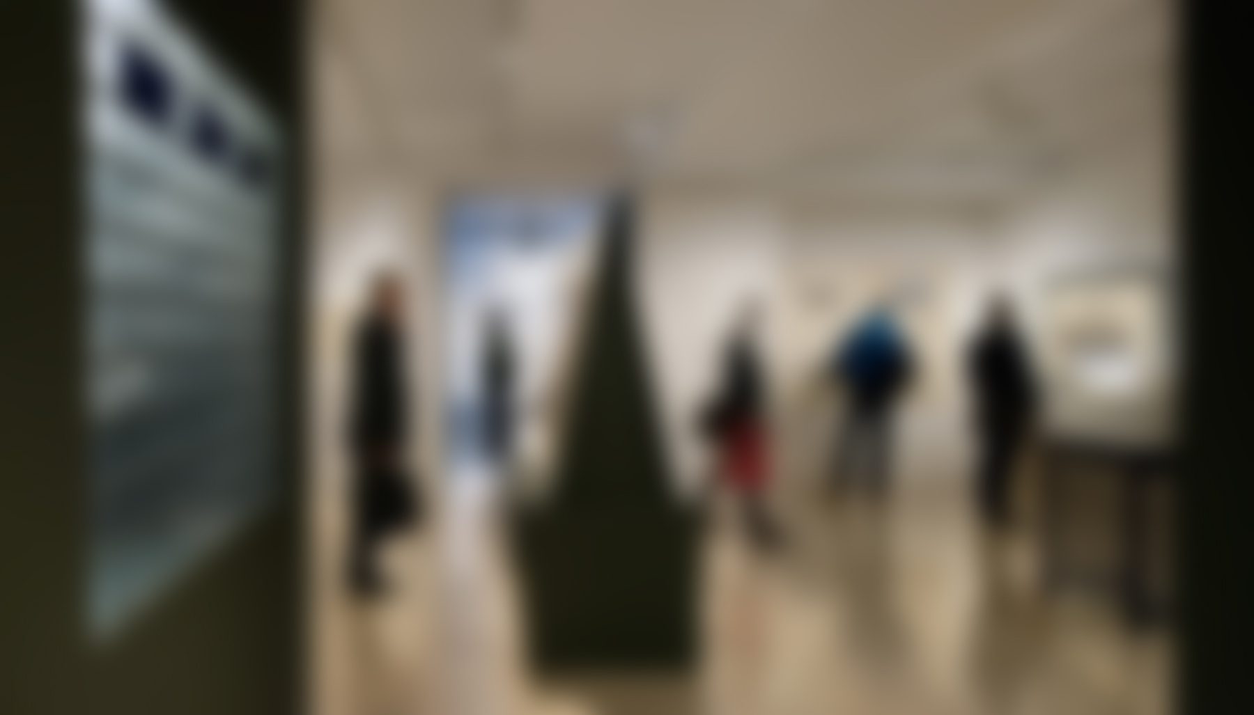 Art gallery visitors viewing abstract sculptures indoors.