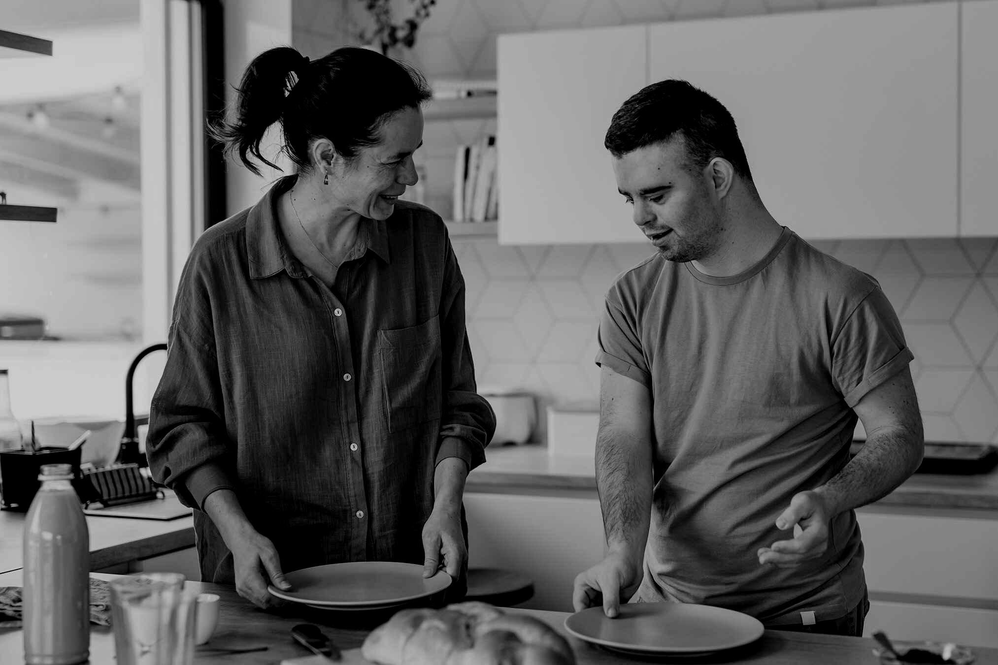 Smiling girl holding a plate talking to a smiling guy at the kitchen island
