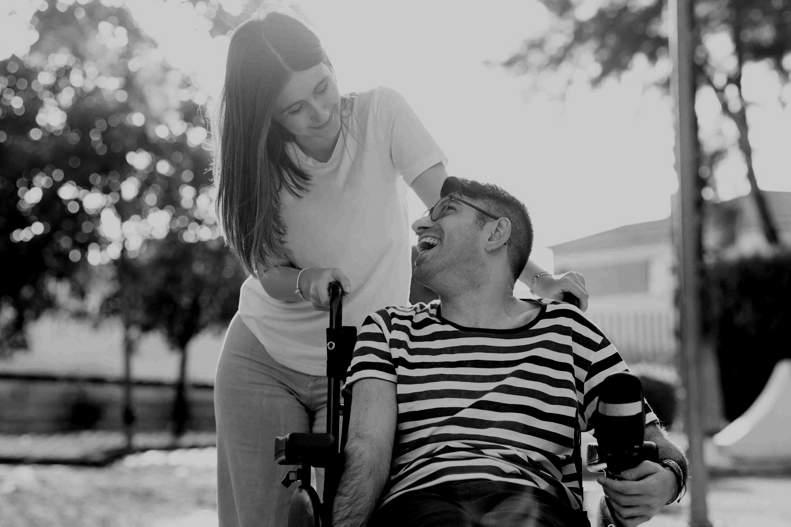 smiling girl pushing a smiling guy on wheelchair